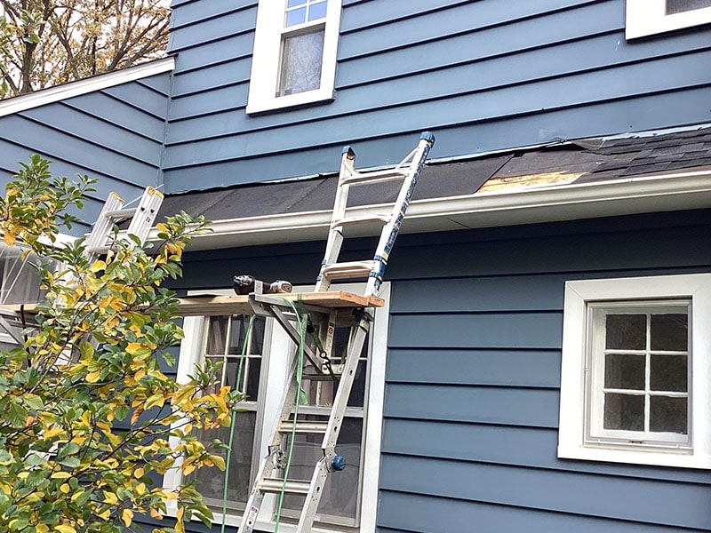 A blue house with a damaged roof that is needing a roof repair in michigan