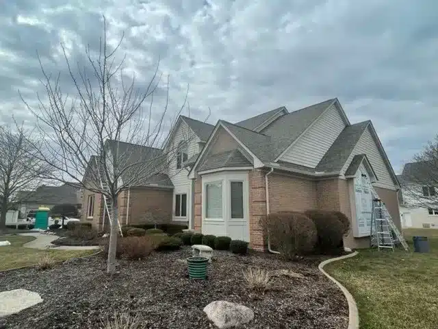 Brick and siding house with a newly installed roof and ongoing construction work by Performance Roofing and Siding in Michigan