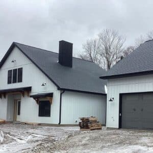 Two-story modern farmhouse with white board and batten siding, black roof, and black framed windows in Michigan