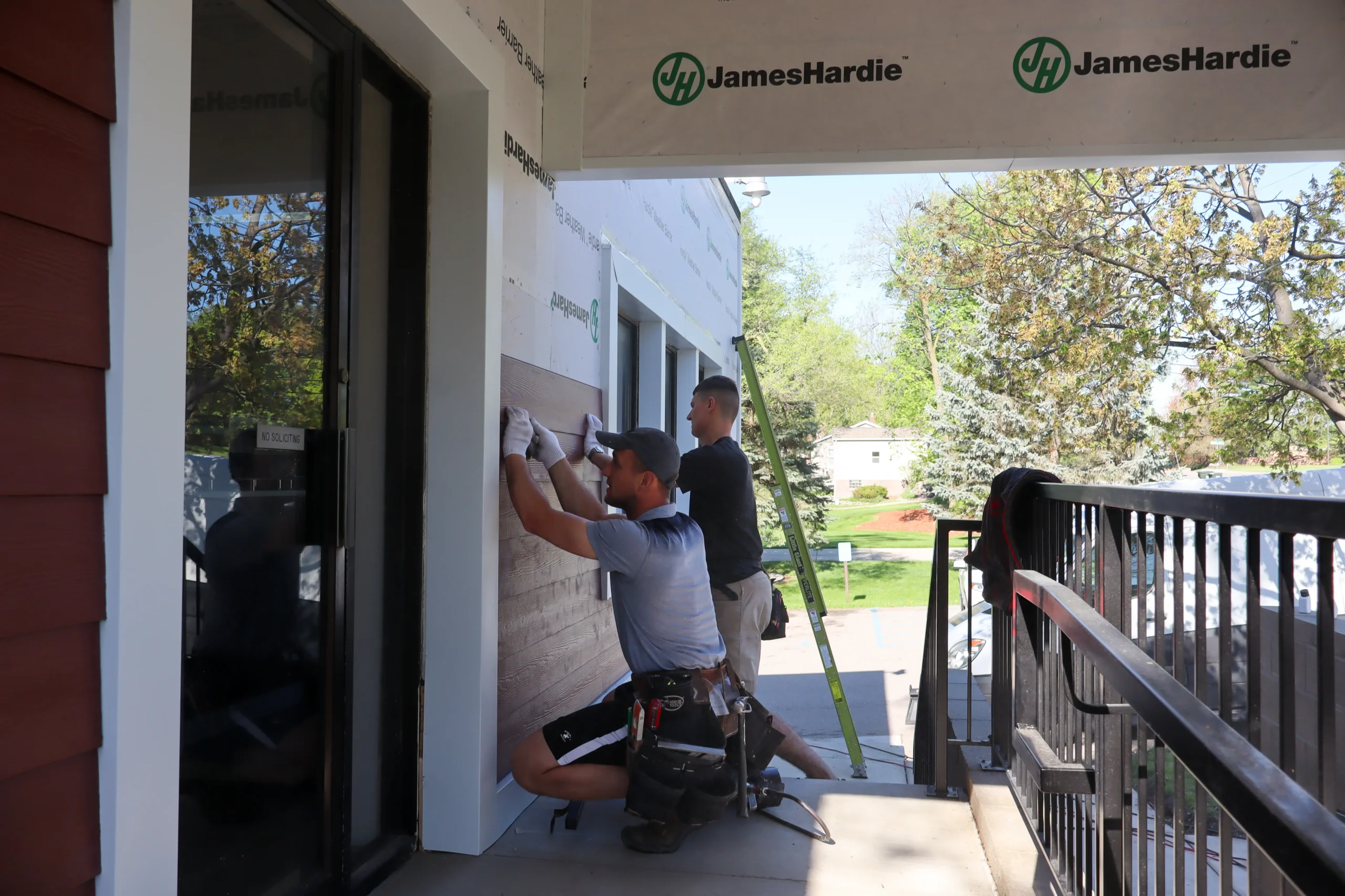 Performance Roofing & Siding contractors installing James Hardie siding on a residential home exterior, demonstrating careful workmanship and professionalism.