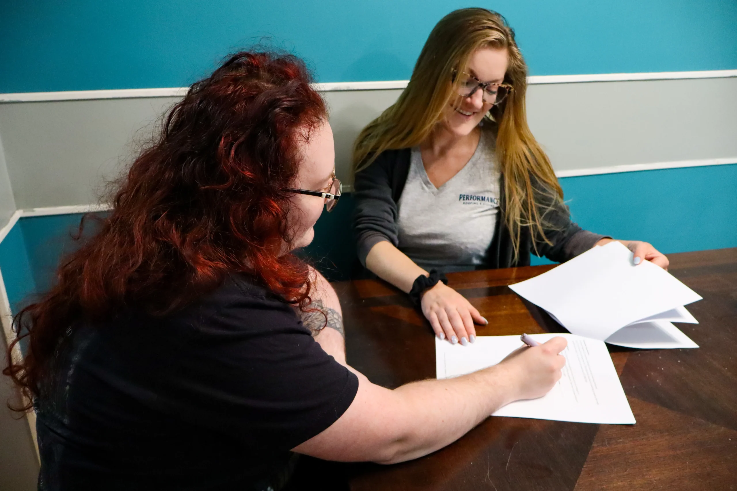Woman signing financing contract with assistance at Performance Roofing and Siding in Ann Arbor, Grand Rapids, and Pontiac