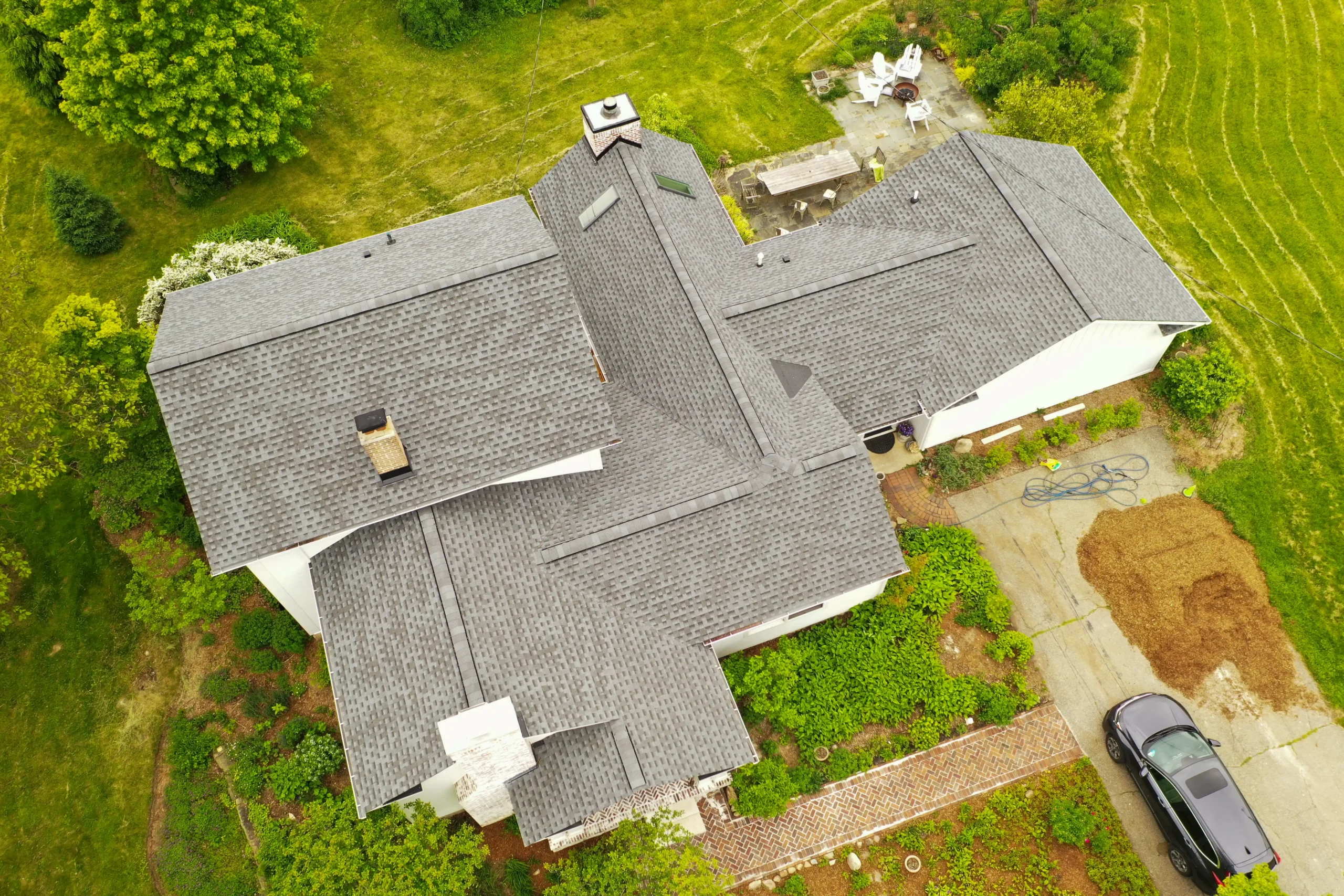 Aerial view of a residential home with a newly installed, well-maintained roof, surrounded by green landscaping, illustrating quality roofing work eligible for the Performance Roofing & Siding Referral Program.
