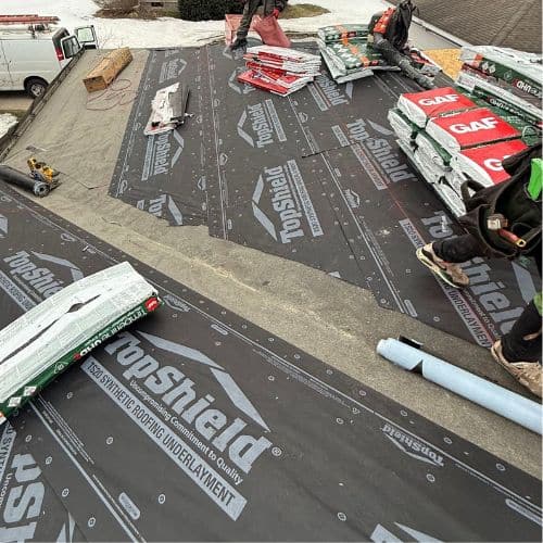 Installation of a new GAF roofing system, including underlayment and bundles of impact-resistant shingles, on a residential roof.