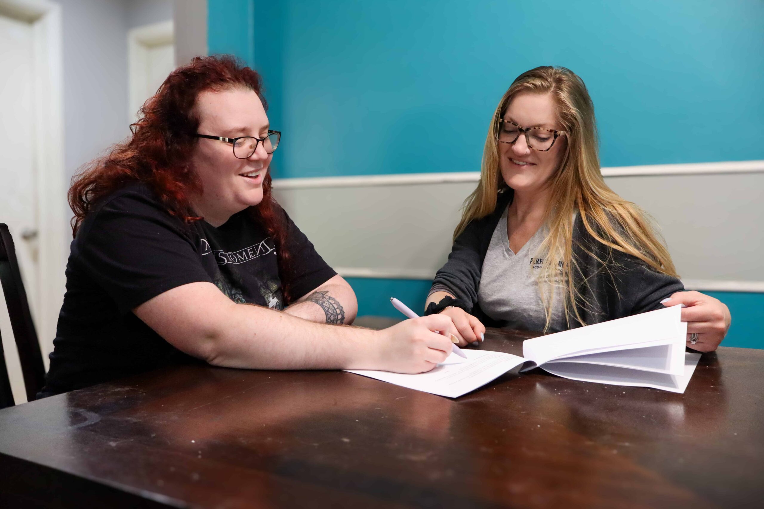 Woman signing financing contract with assistance at Performance Roofing and Siding in Ann Arbor, Grand Rapids, and Pontiac