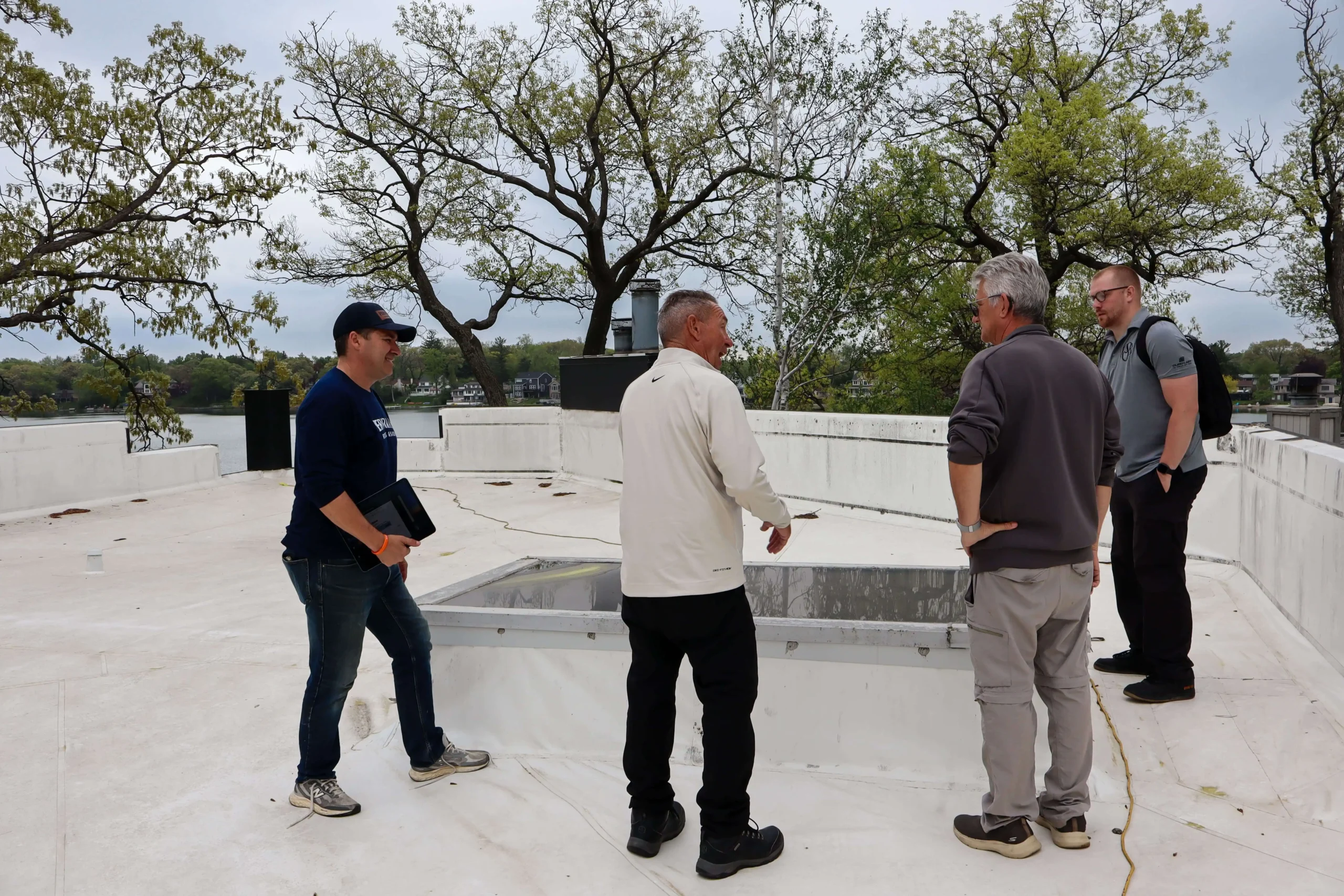 Performance Roofing & Siding commercial roofing specialists and clients discussing project details on a flat commercial roof, demonstrating collaborative inspection and planning.
