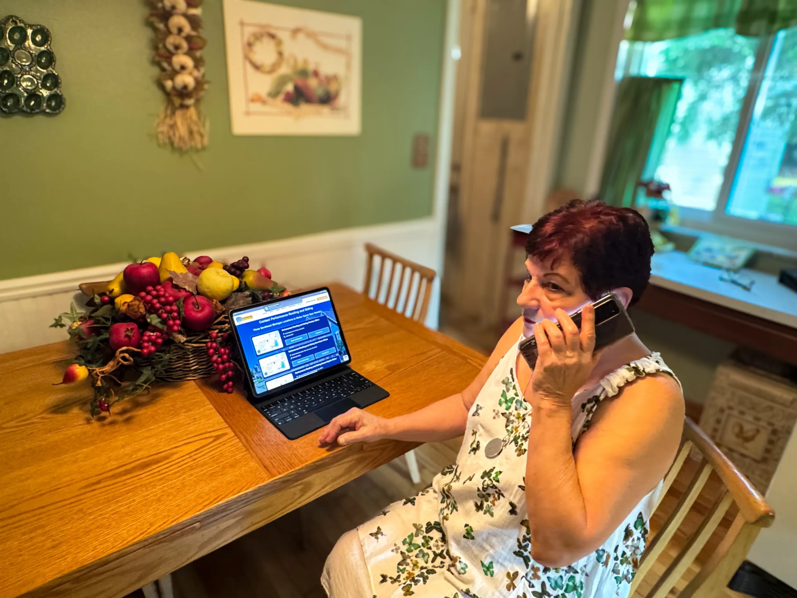 Woman contacting Performance Roofing and Siding for a quote using a tablet and phone at home