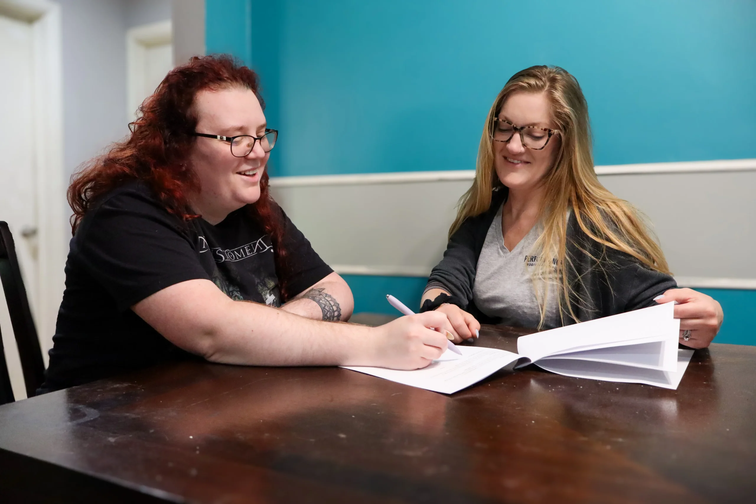 Performance Roofing & Siding team member assisting a customer with paperwork at a table, highlighting personalized roofing services available in Southern Michigan.