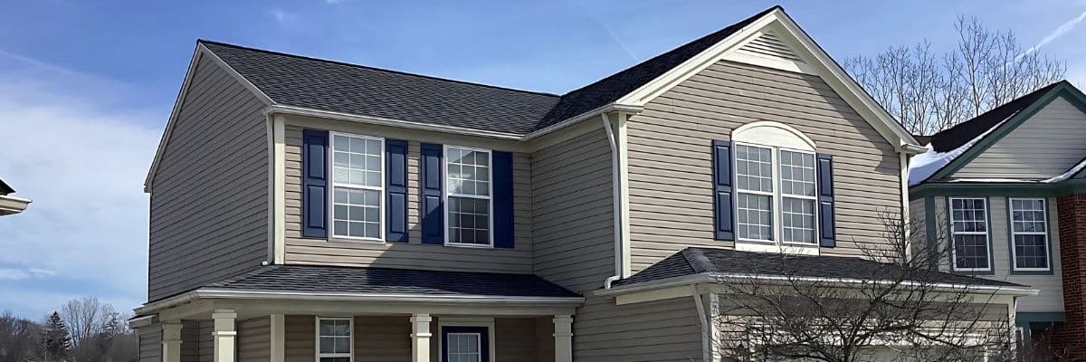 A newly installed, dark gray GAF impact-resistant shingle roof on a well-maintained suburban home by Performance Roofing & Siding